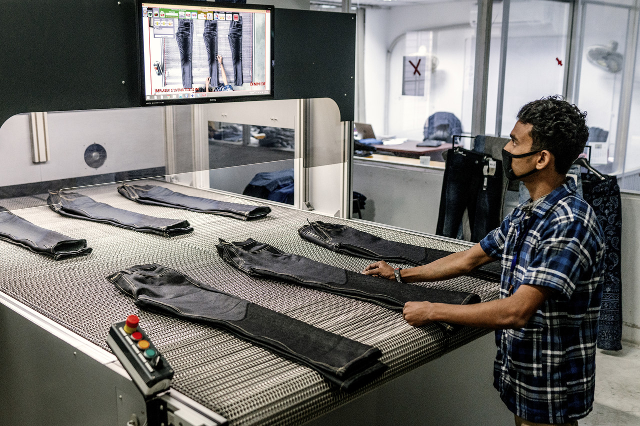 A worker uses a laser engraving machine to distress jeans at Denim Expert Ltd